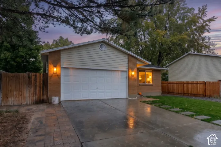 Exterior featuring brick and horizontal siding, attached two-car garage, concrete driveway, and wooden privacy fencing