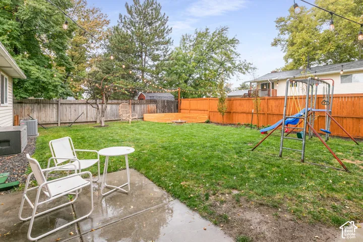 Fenced backyard featuring a concrete patio, wood-finish privacy fencing, and string lighting