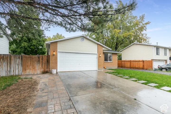 Exterior facade featuring brick and horizontal siding, an attached two-car garage, paved driveway, and stone-paver hardscaping