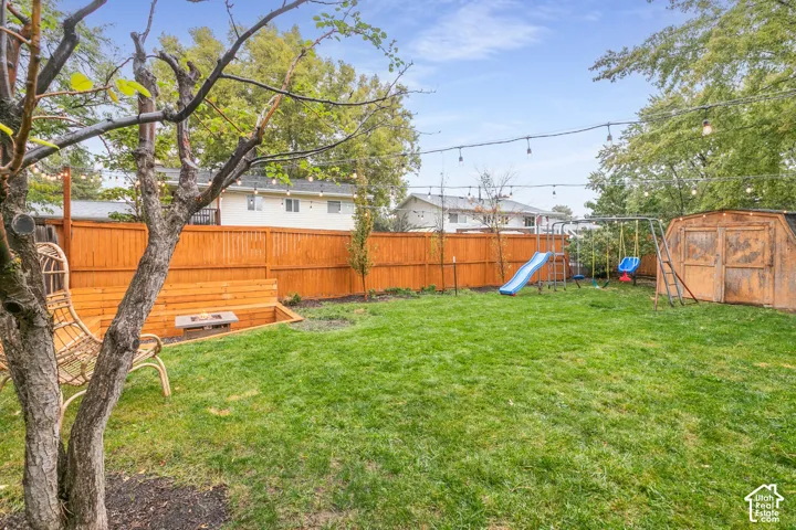 Private backyard featuring a full-height wood privacy fence, integrated wooden bench seating, and overhead string lighting
