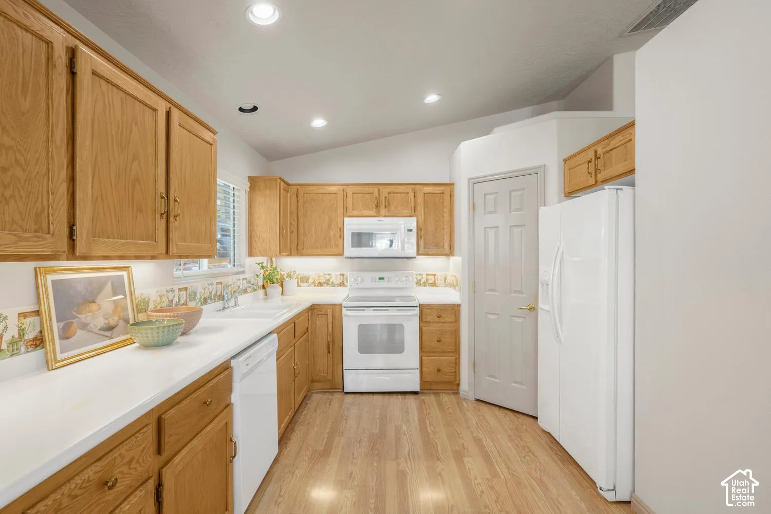 Kitchen featuring wood cabinetry, white solid-surface countertops, wood-finish flooring, and recessed ceiling lighting