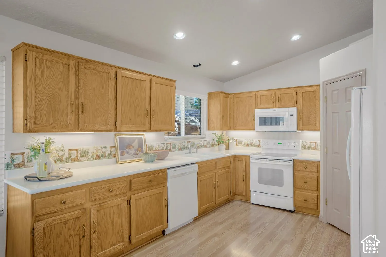 Kitchen featuring natural wood cabinetry, white countertops, recessed ceiling lighting, light wood-finish flooring, and a built-in microwave