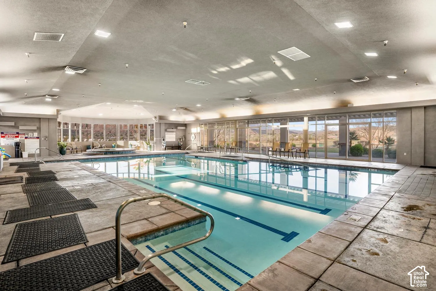 Indoor swimming facility featuring a lap pool, integrated hot tub, extensive tile flooring, recessed lighting, and floor-to-ceiling windows