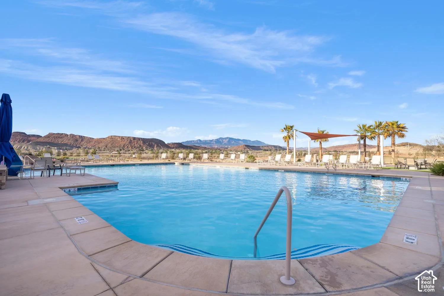 Swimming pool with concrete decking, metal handrails, and mountain backdrop