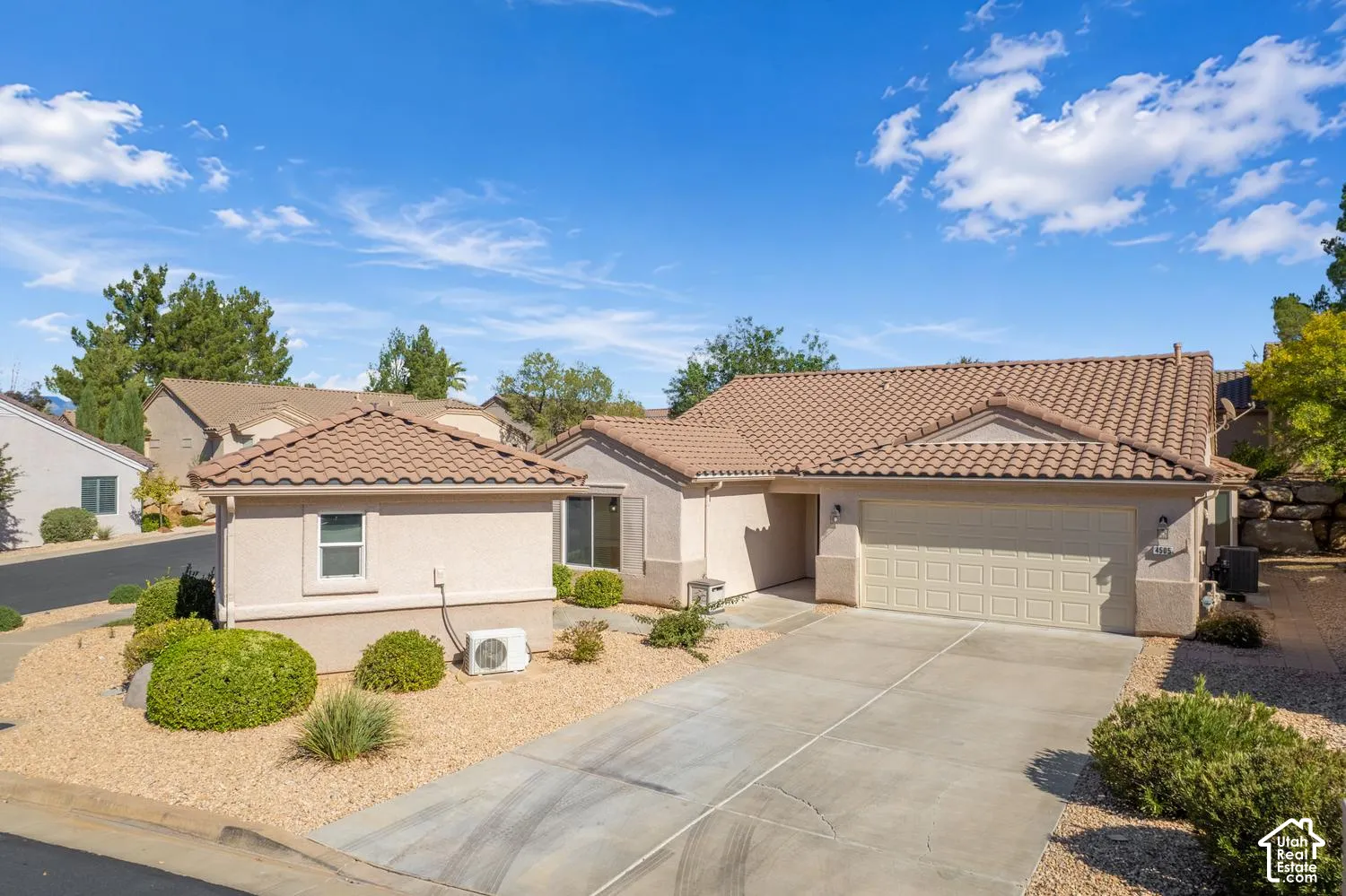 Single-story exterior featuring a tile roof, stucco siding, a concrete driveway, and an attached two-car garage