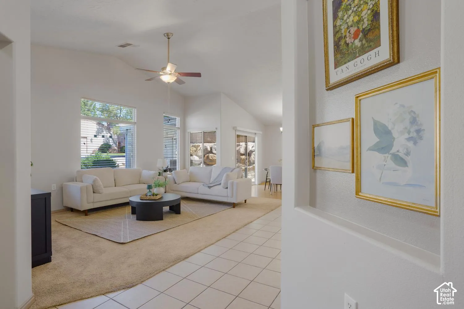 Vaulted ceilings, expansive windows, ceramic tile flooring, and a ceiling fan