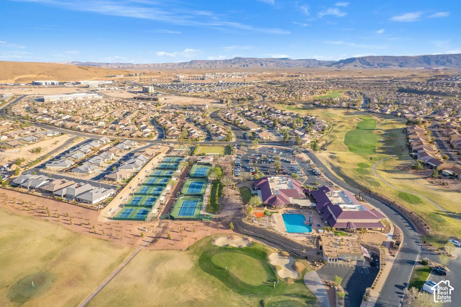 Aerial perspective of a community facility featuring multiple tennis courts, a swimming pool, and proximity to a golf course