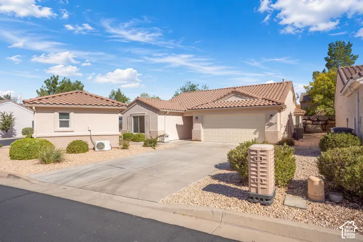 Single-story residence featuring a tile roof, stucco exterior, concrete driveway, and low-maintenance desert landscaping