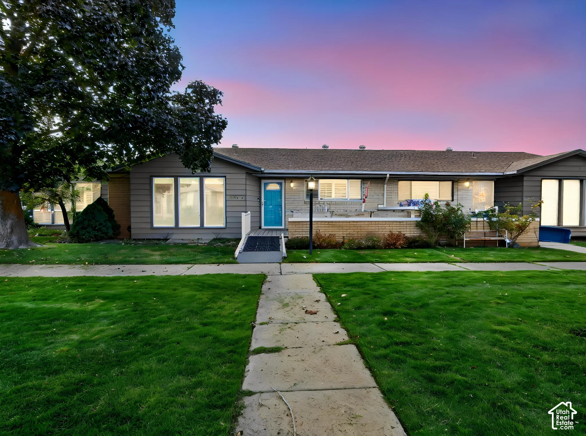Single-story residence with horizontal siding, brick masonry detailing, an expansive front lawn, and a ramp-accessible entrance