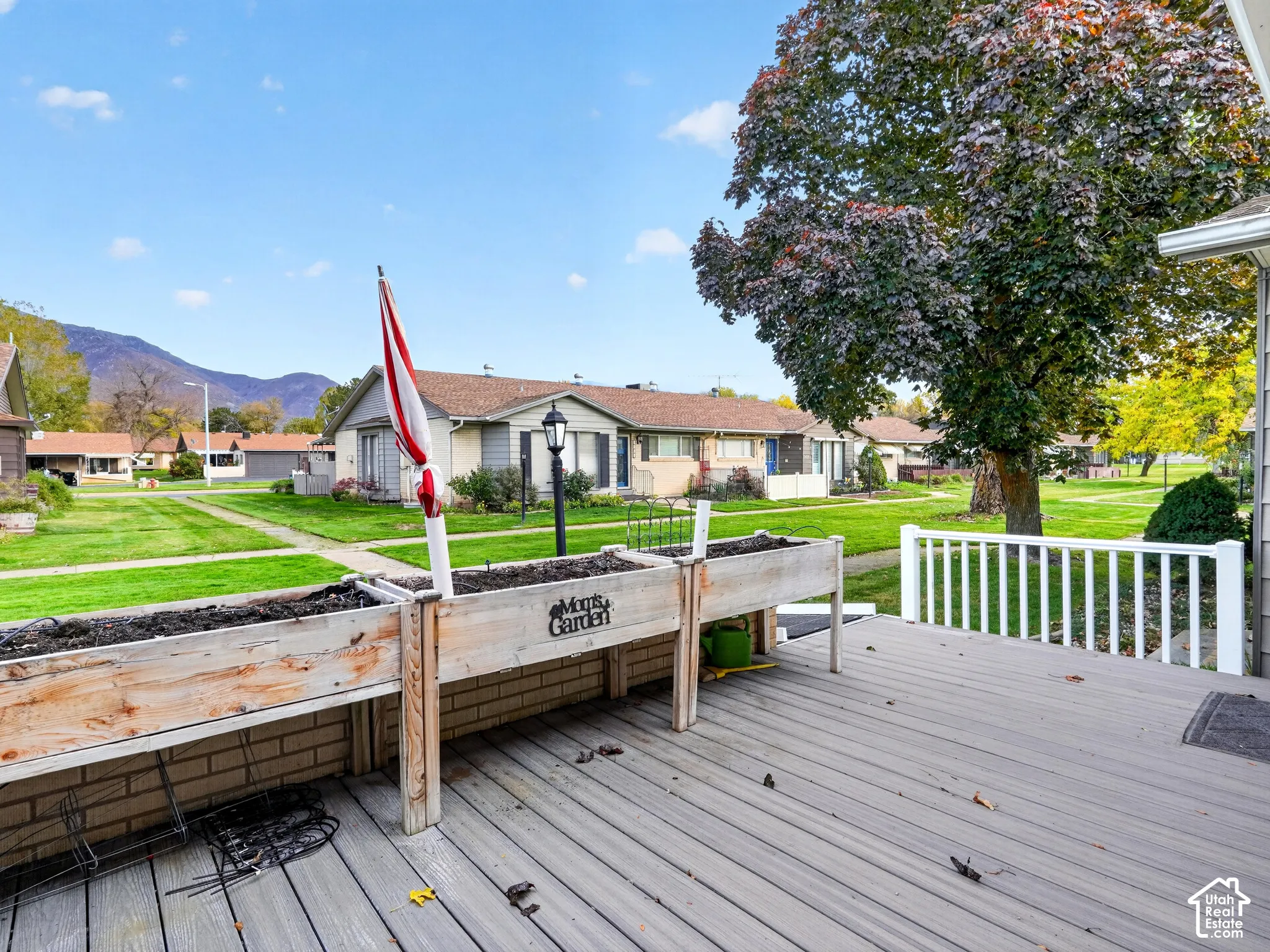 Outdoor deck featuring composite decking, white railing, built-in wooden planters, and mountain surroundings
