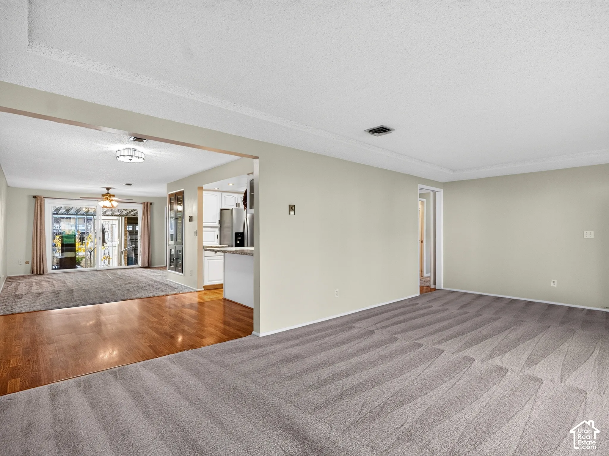 Open-concept interior featuring neutral-toned walls, wood-finish flooring, wall-to-wall carpeting, and sliding glass doors