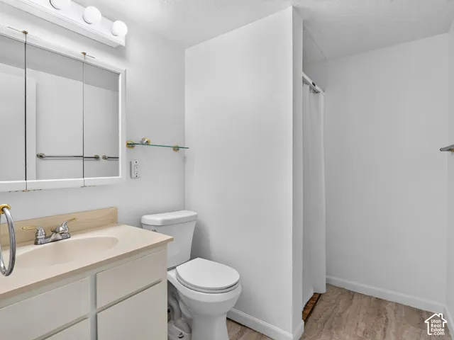 Bathroom featuring a white vanity cabinet, a solid-surface countertop with an integrated basin, a tri-fold mirrored medicine cabinet, and stone-finish flooring