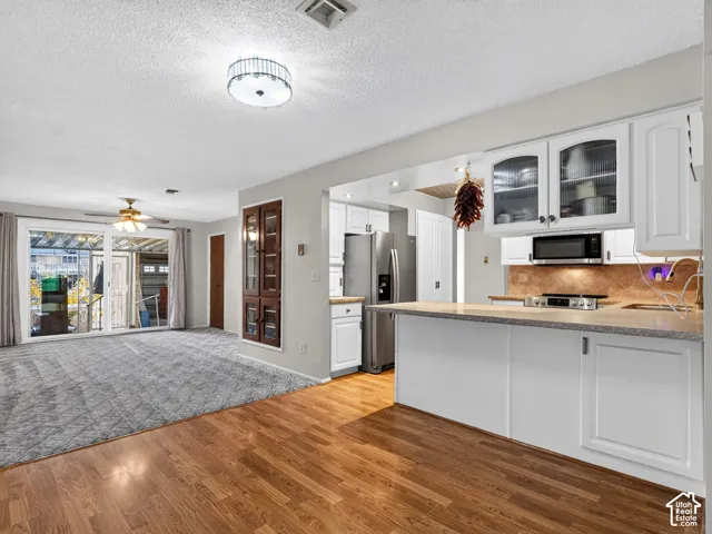 Kitchen featuring white cabinetry, stone-surface countertops, built-in microwave, and stainless steel refrigerator, complemented by wood-finish flooring