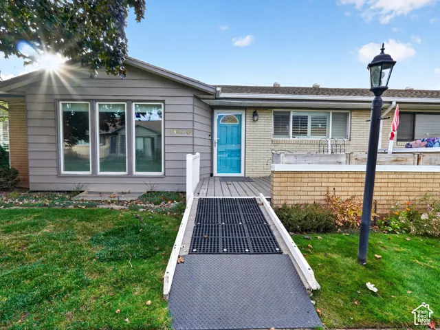Single-story residence featuring a mixed-material exterior of horizontal siding and brick, a front deck with metal ramp access, and a decorative lamp post