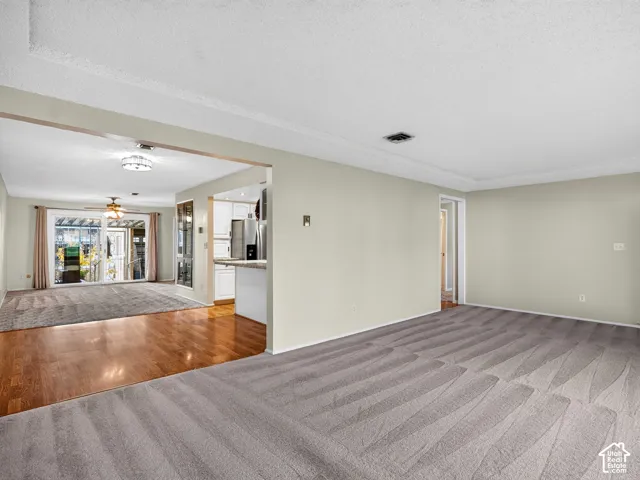 Open-concept interior featuring neutral-toned walls, wood-finish flooring, wall-to-wall carpeting, and sliding glass doors