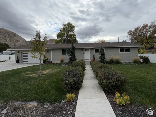 Single-story residence featuring light-toned brick exterior, asphalt shingle roof, attached two-car garage with modern paneled door, and concrete walkway