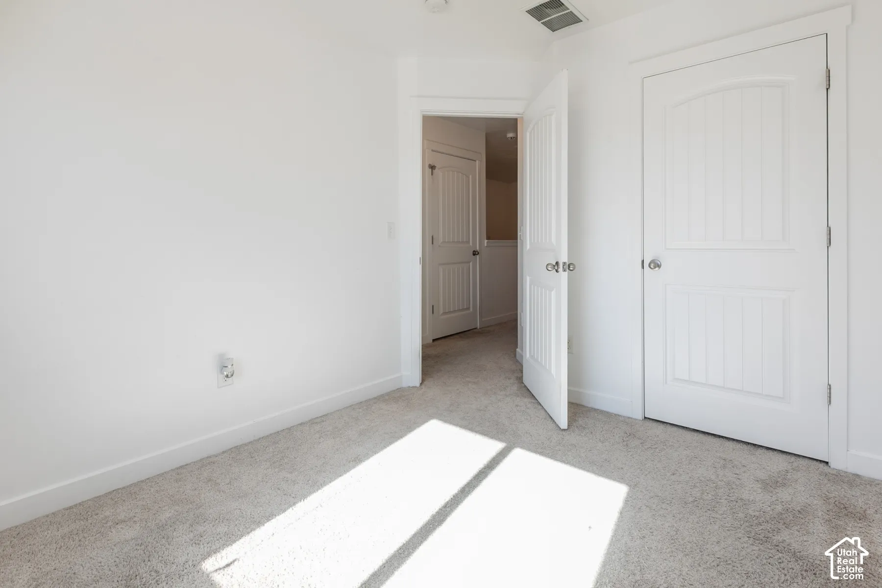 Interior room featuring neutral-toned carpeting and two-panel arched interior doors with polished chrome hardware