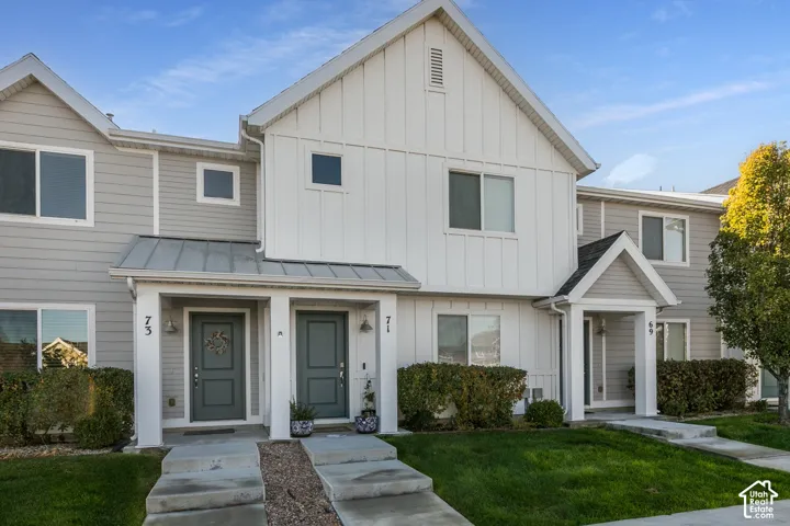 Multi-family exterior featuring vertical board-and-batten and horizontal siding, metal porch roofing, concrete walkways, and individual covered entryways