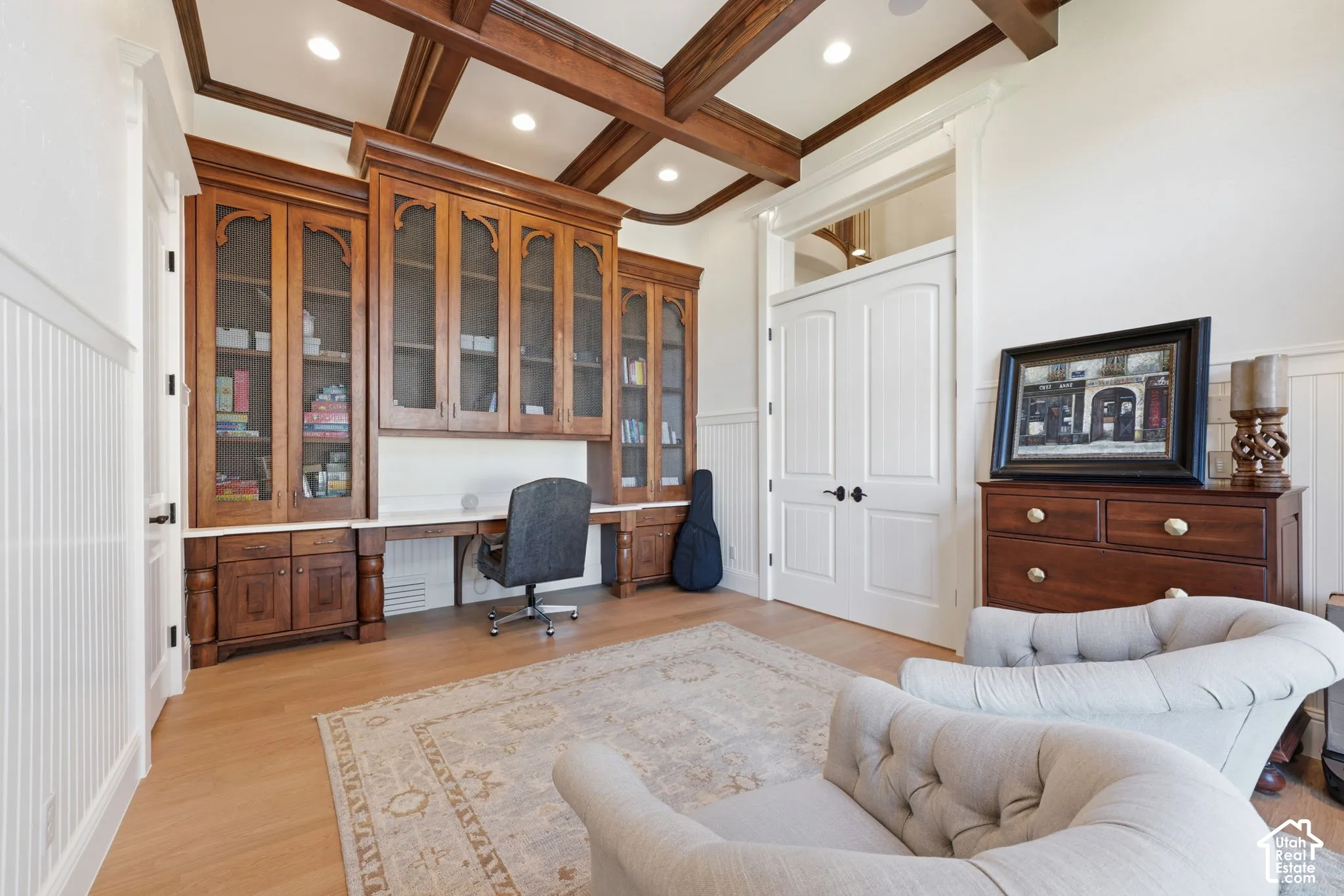 Custom built-in wood cabinetry with integrated desk space, coffered ceiling with exposed wood beams, wood-finish flooring, and double doors with transom window