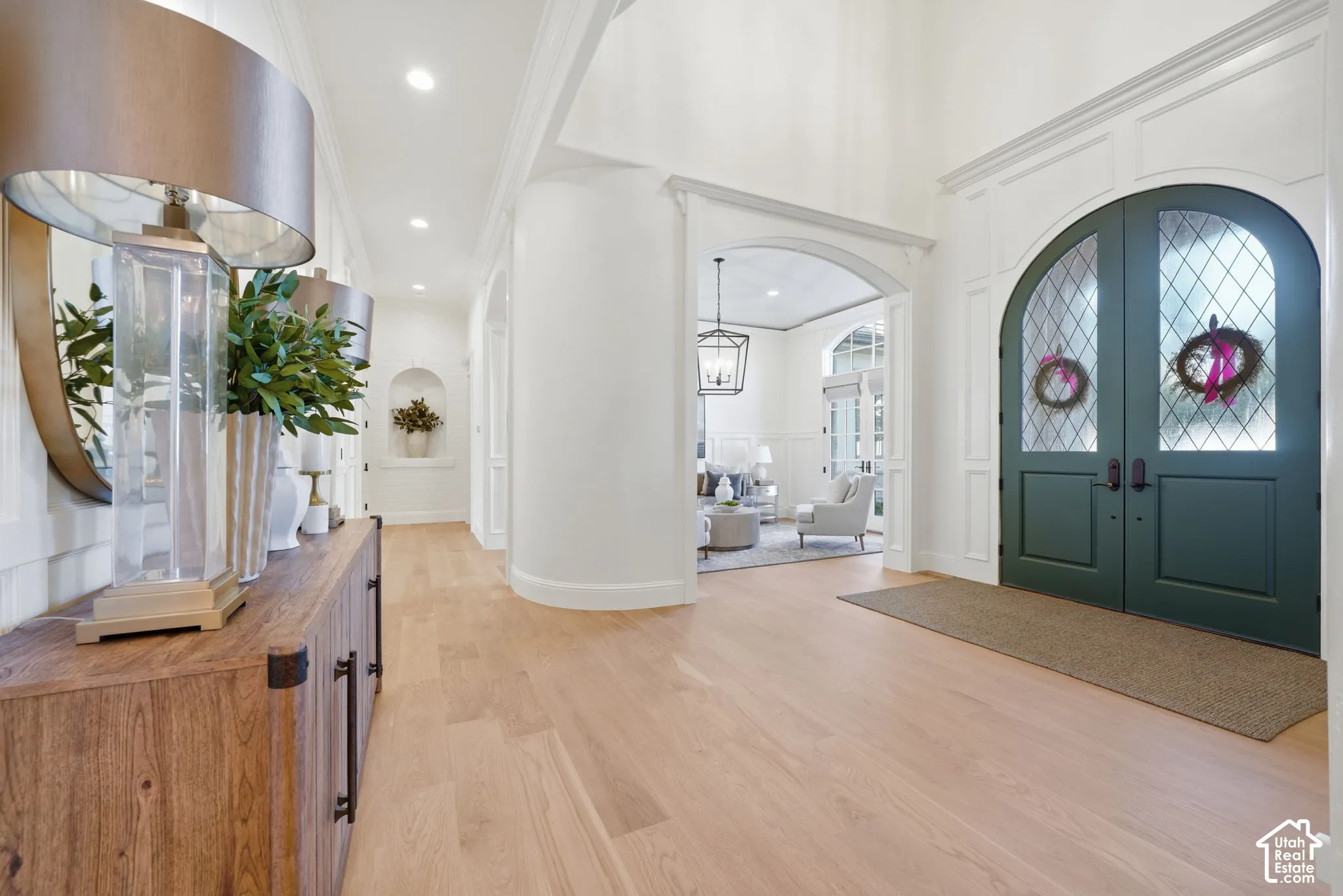 Foyer featuring double-entry arched doors with diamond-pane glass, wood-finish flooring, curved architectural wall detailing, recessed wall niche, and vaulted ceiling