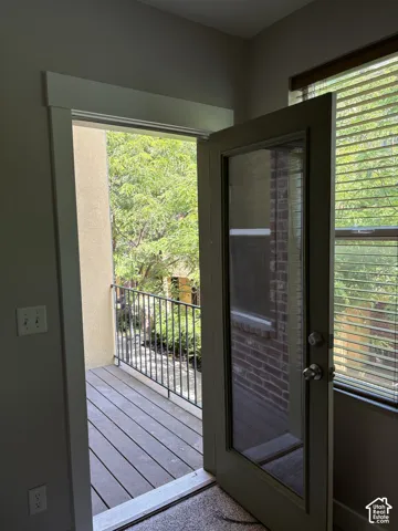 Full-lite exterior door with metallic hardware, providing access to a private balcony featuring composite decking and a metal railing