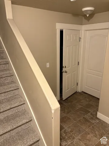Carpeted staircase with painted wooden handrail, tiled flooring, and paneled interior doors