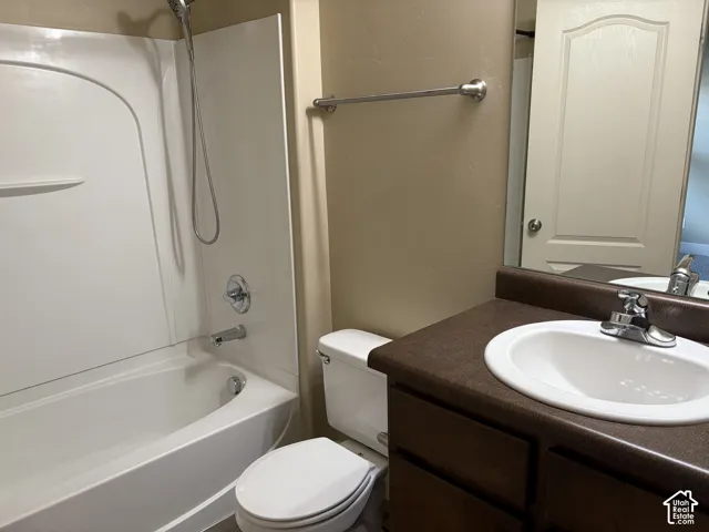 Bathroom featuring a soaking tub and shower combination with a molded surround, a vanity with a dark-tone countertop and under-mount basin, and a metal-finish towel bar