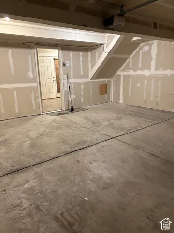 Garage featuring concrete flooring, unfinished drywall, overhead door motor, and an interior access door