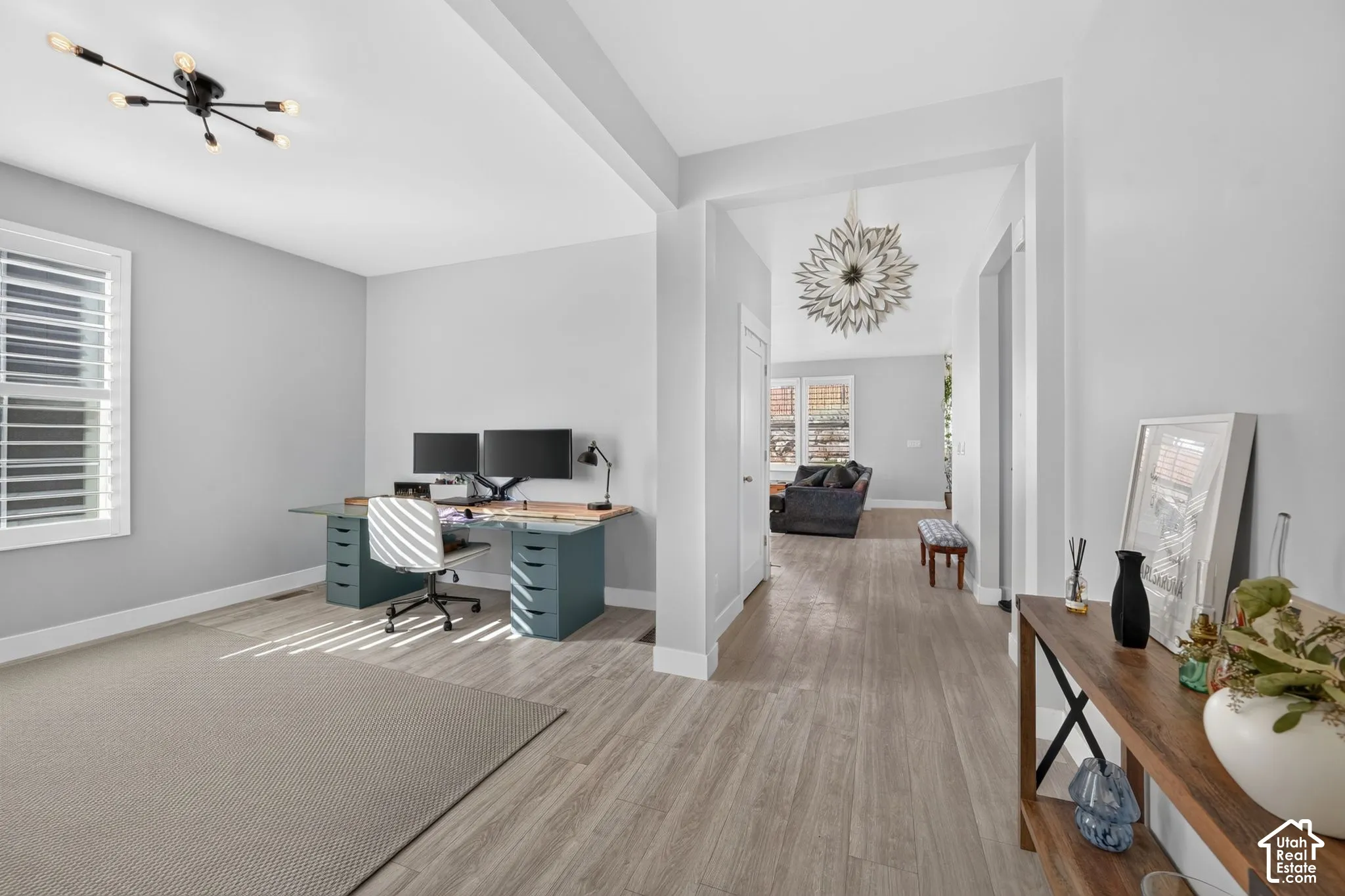 Wood-finish flooring, multi-light ceiling fixture, window with shutter blinds, and neutral wall tones