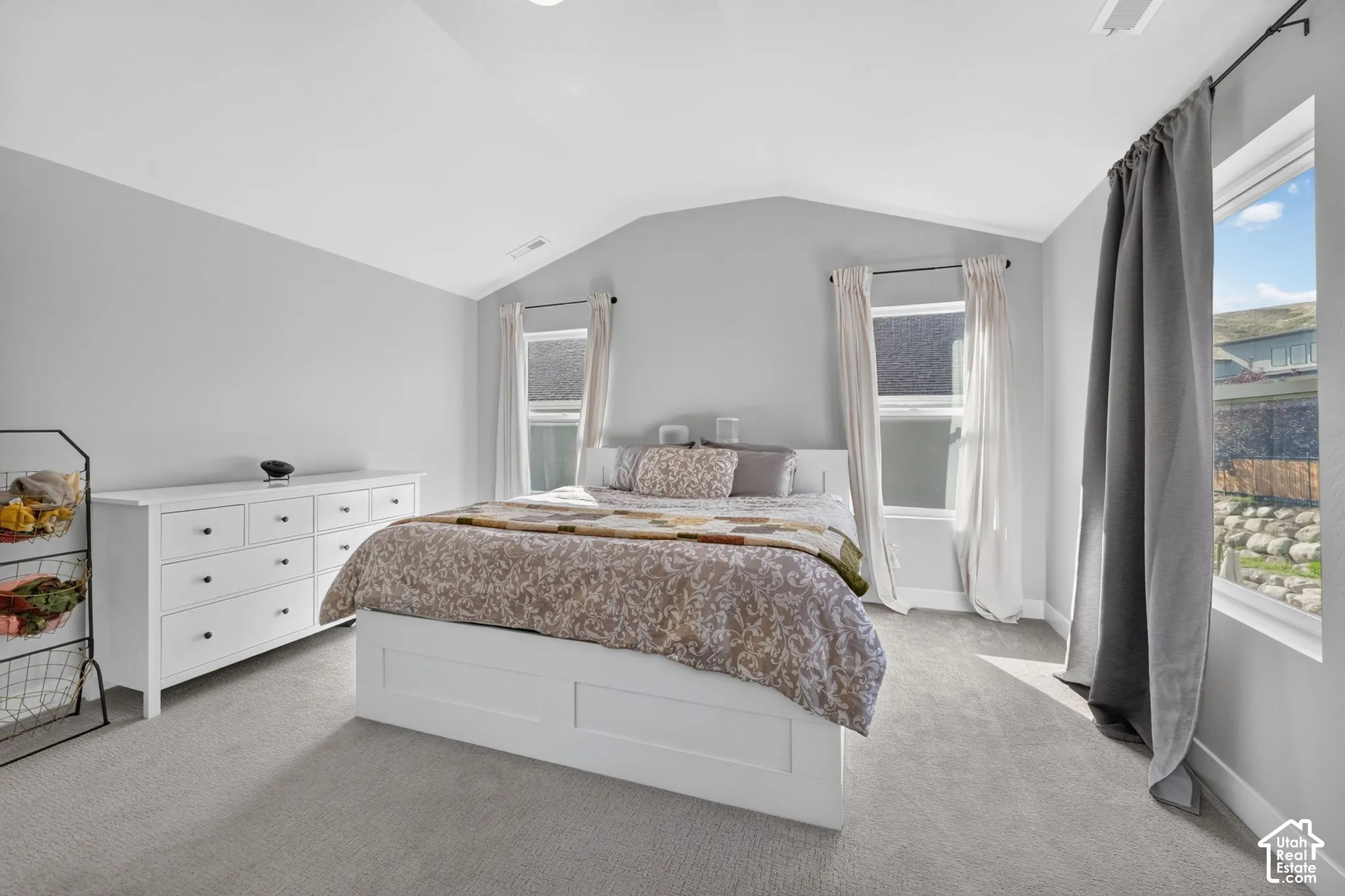 Vaulted ceiling, neutral wall tones, wall-to-wall carpeting, and multi-pane windows