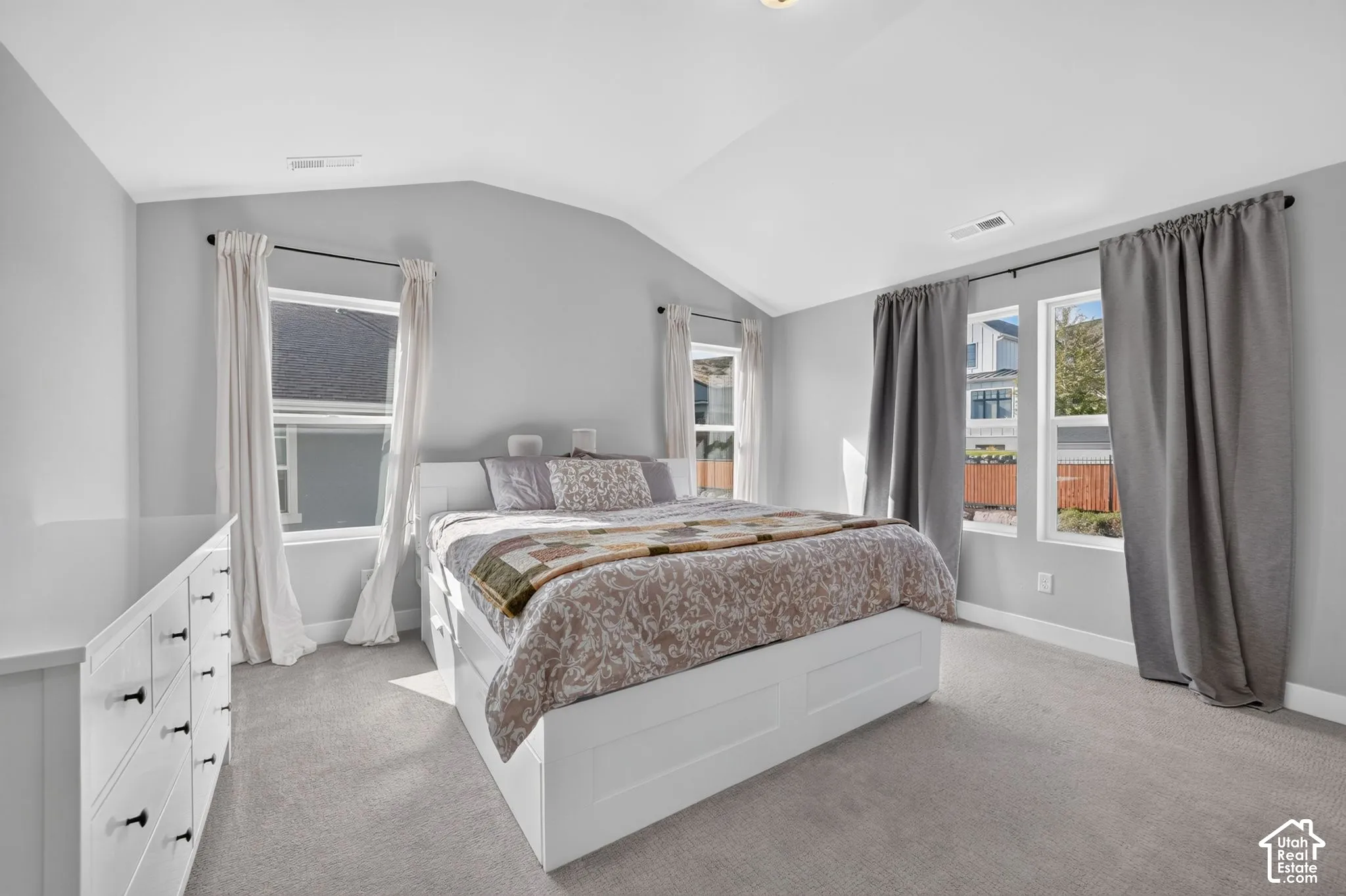 Vaulted ceilings featuring neutral wall paint, carpeting, and multiple windows