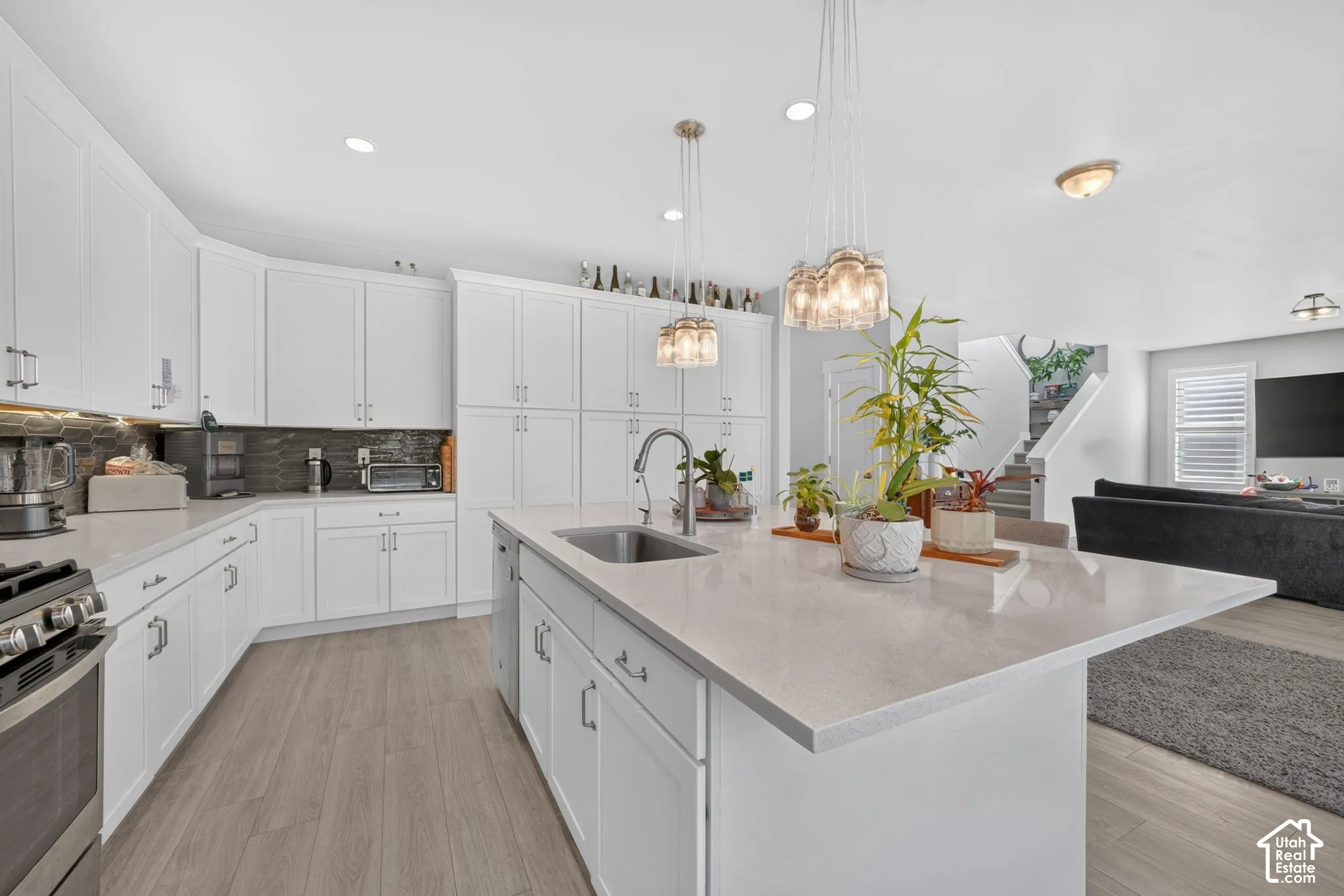 Kitchen featuring white cabinetry, quartz countertops, a central island with an undermount sink, and wood-finish flooring