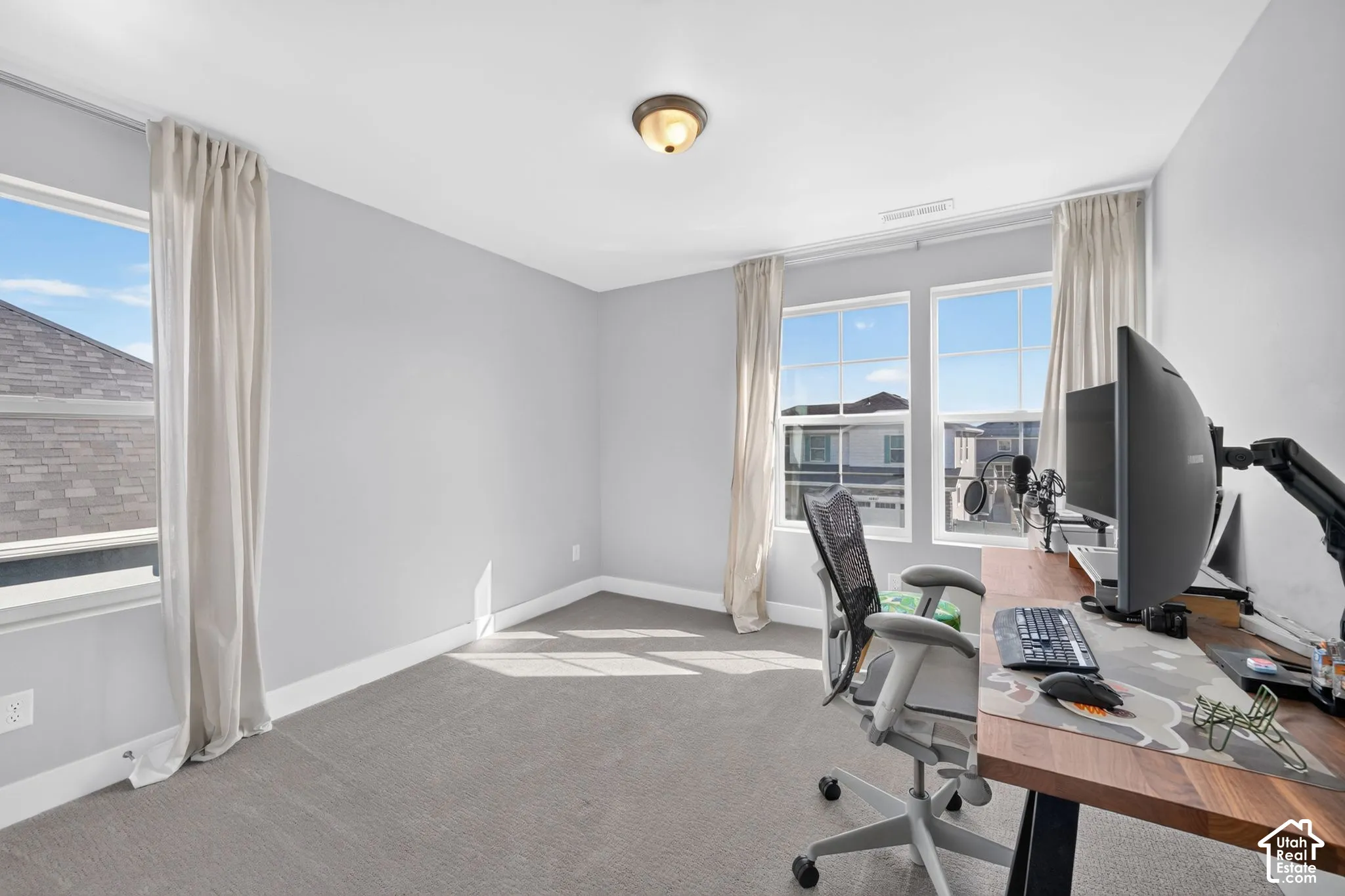 Neutral-toned interior featuring wall-to-wall carpeting, multiple windows with grid detailing, and a central ceiling-mounted light fixture