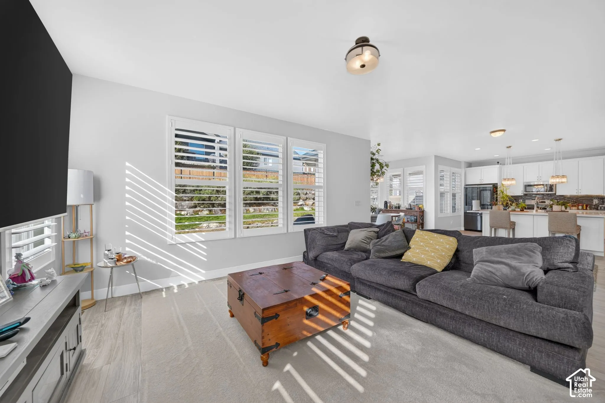 Open floor plan featuring wood-finish flooring, white cabinetry, plantation shutters, and recessed lighting