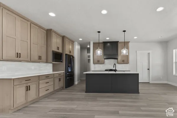 Kitchen featuring light wood-finish cabinetry, quartz countertops, a charcoal-toned center island, white subway tile backsplash, and recessed lighting