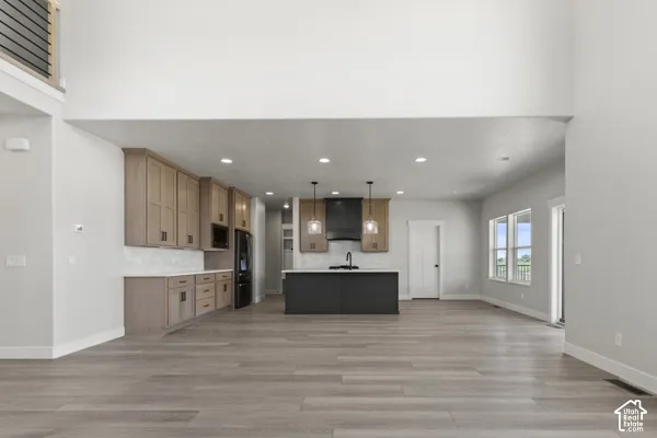 Kitchen featuring wood-finish cabinetry, a contrasting center island with a matte finish, wood-finish flooring, recessed lighting, and dual pendant fixtures