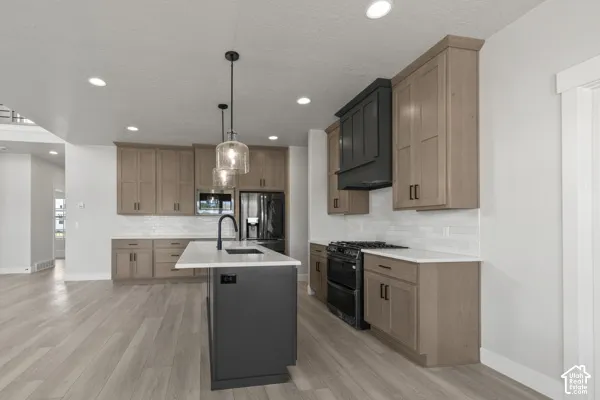 Kitchen featuring wood-finish cabinetry, a contrasting center island with a quartz countertop, recessed lighting, glass pendant fixtures, and a matte black range hood