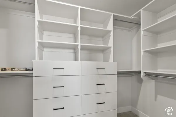 Custom built-in storage system featuring floor-to-ceiling white shelving, six soft-close drawers with matte black hardware, and integrated hanging rods