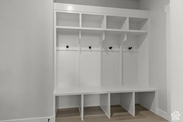 Built-in white mudroom cabinetry featuring four open upper compartments, integrated bench seating, lower storage cubbies, and matte black wall-mounted hardware