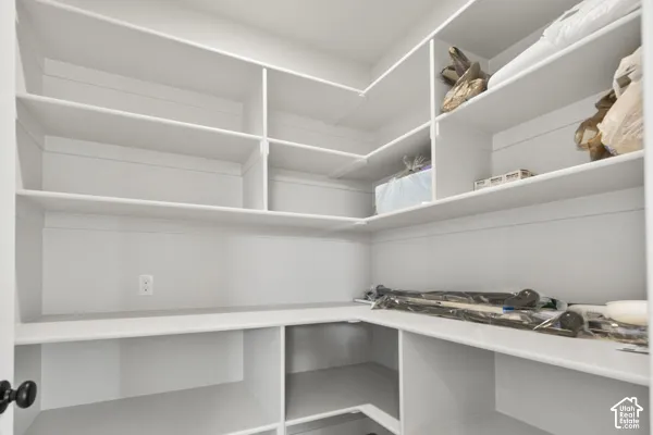 Walk-in pantry featuring white custom built-in shelving and corner storage configuration