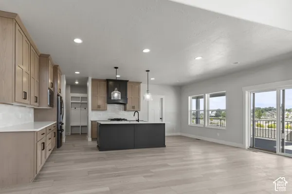 Kitchen featuring light-finish cabinetry, a dark-toned central island, wood-finish flooring, quartz countertops, and a sliding glass door