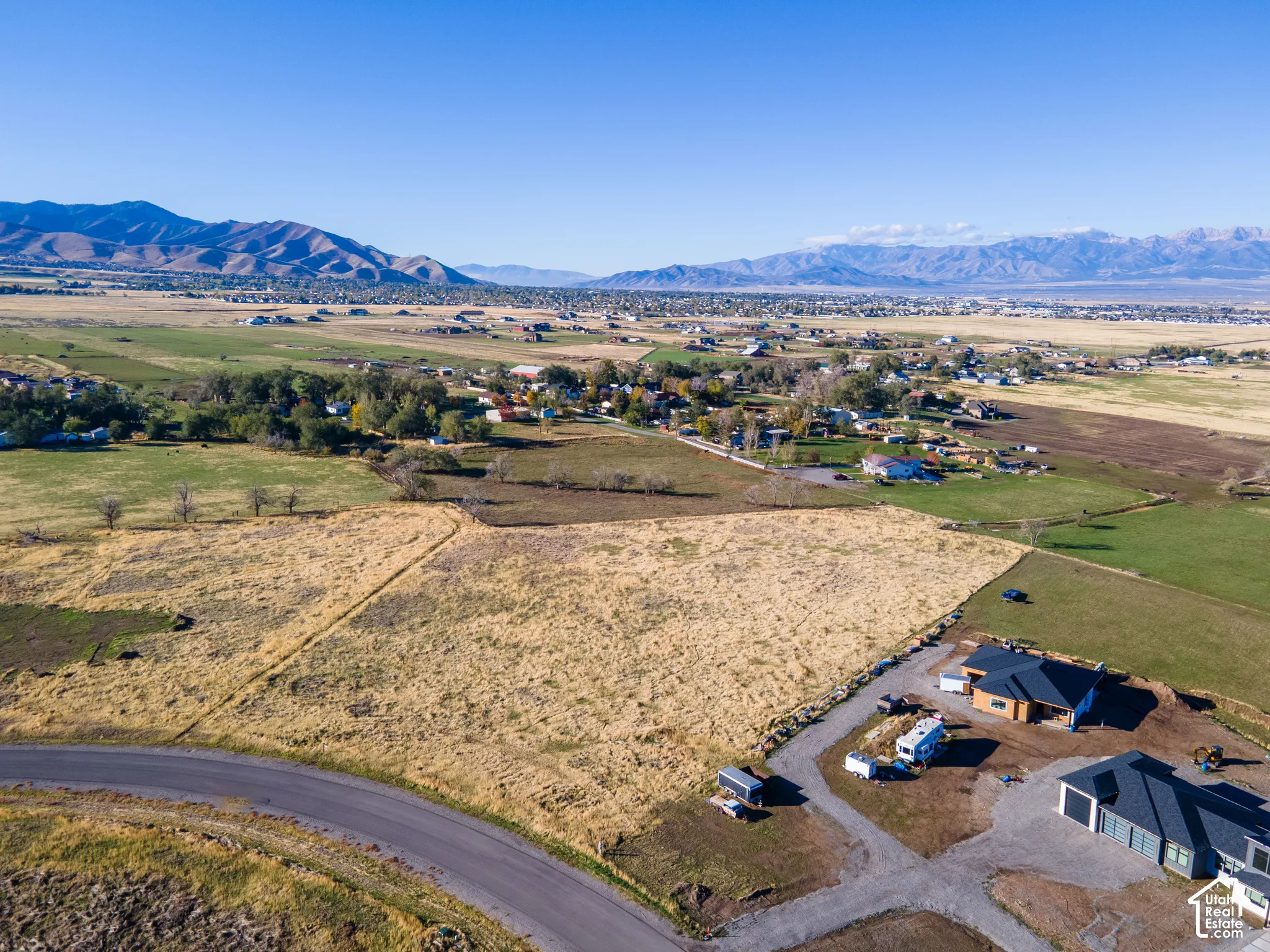 Aerial perspective of expansive acreage featuring mountain range backdrops, level terrain, and paved road access