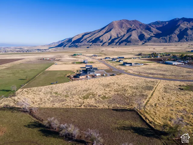 Aerial perspective featuring expansive acreage, natural topography, and a prominent mountain backdrop