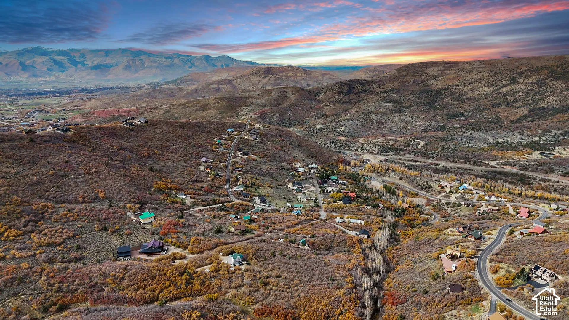 Aerial perspective of mountainous terrain featuring rugged topography, scattered native vegetation, and expansive mountain range horizons