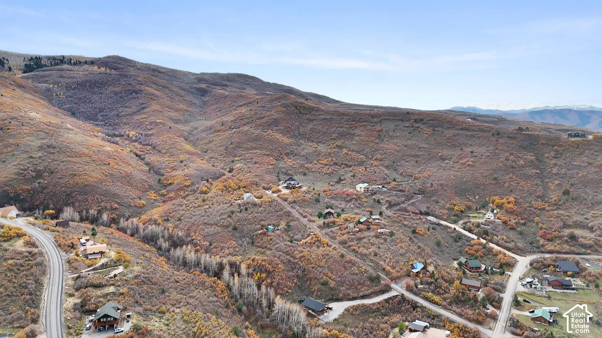 Aerial perspective of mountainous terrain featuring dense natural vegetation and paved access roads