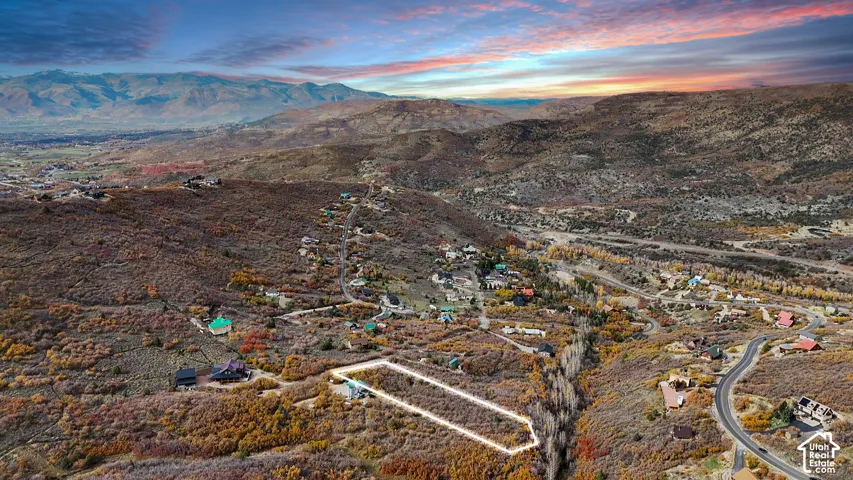 Aerial perspective featuring a hillside lot with mountain range backdrop and native vegetation