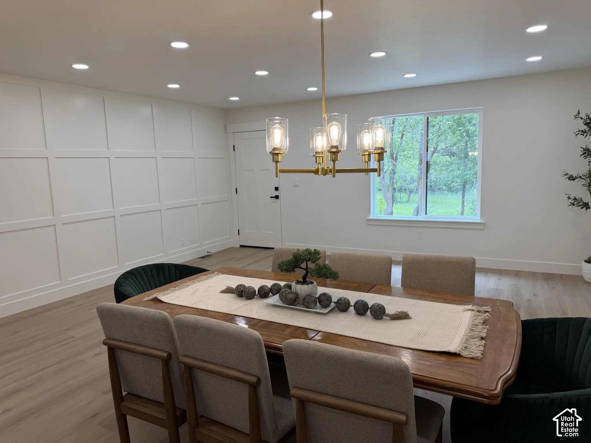 Room featuring decorative wall paneling, recessed lighting, wood-finish flooring, and a multi-arm brass finish chandelier