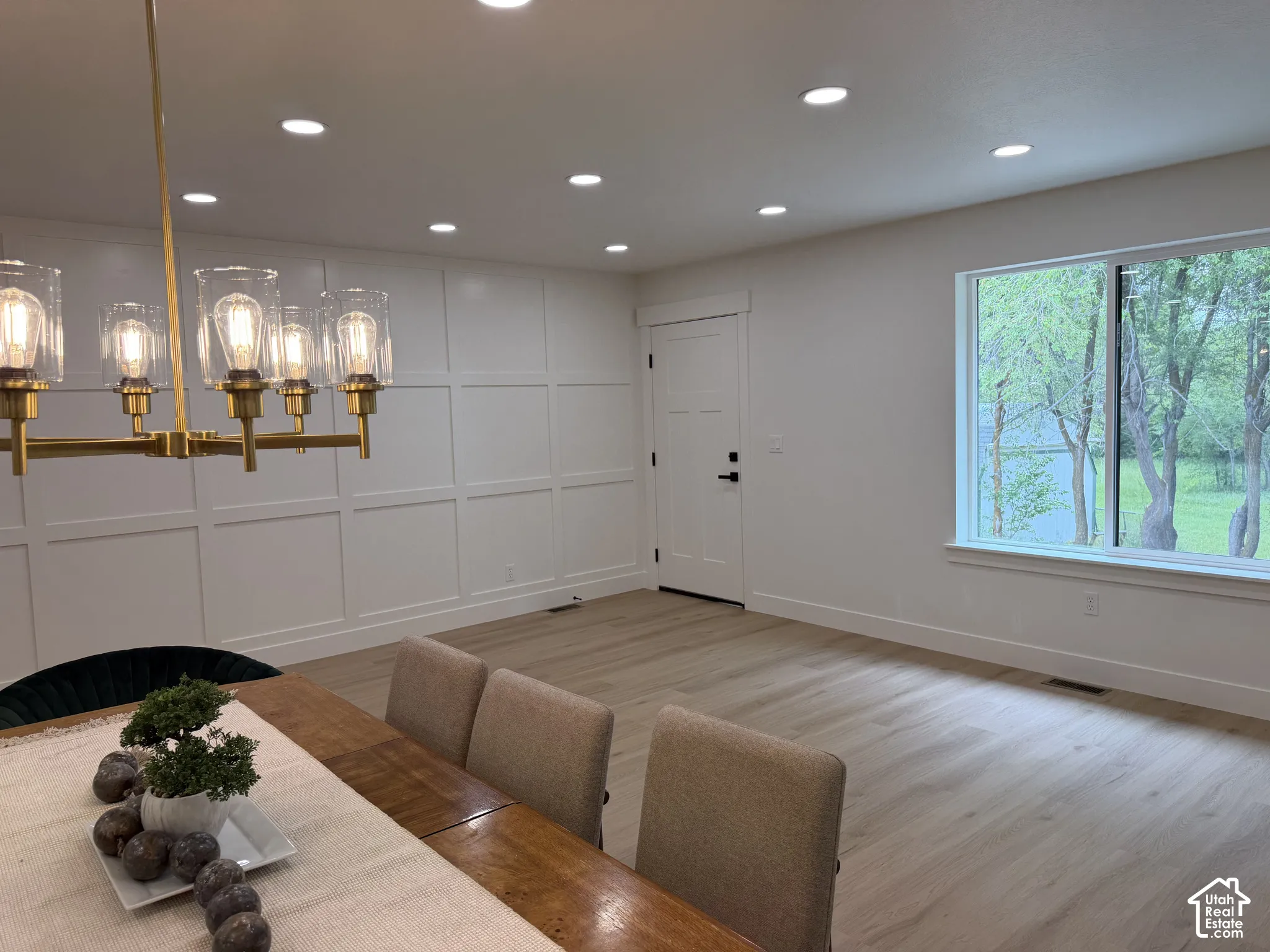 Board-and-batten accent wall, wood-finish flooring, multi-light metal chandelier, and recessed lighting