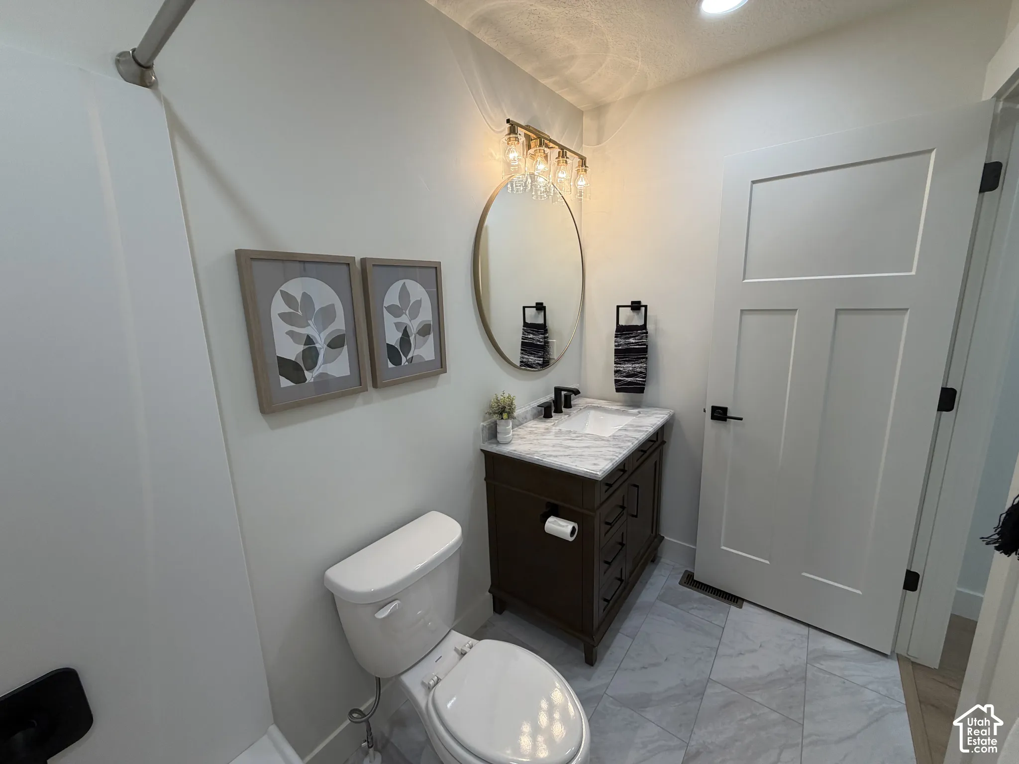 Bathroom featuring a vanity with stone countertop, vessel sink, circular mirror, multi-light fixture, and tile flooring