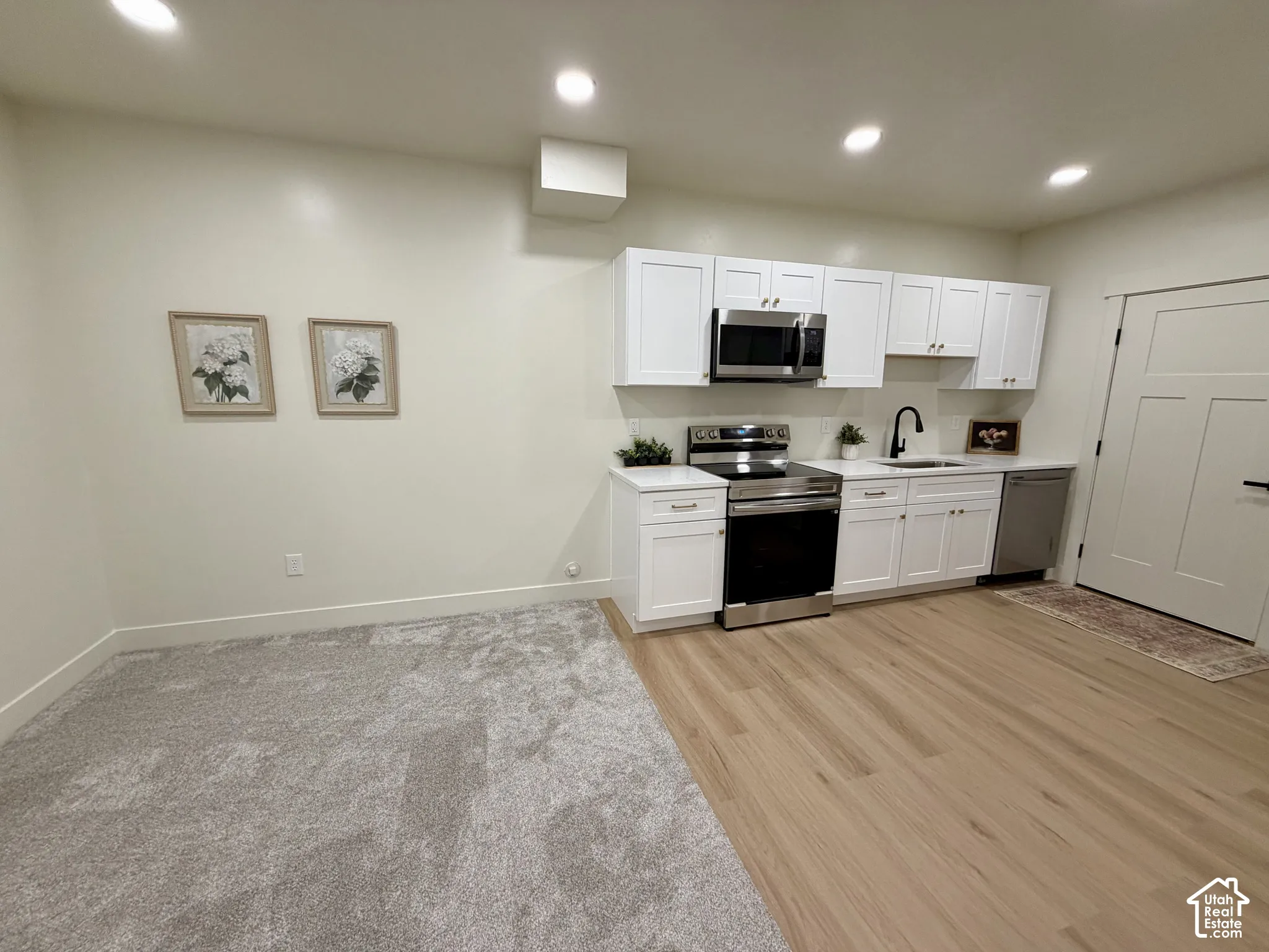 Kitchen featuring shaker-style cabinetry, stainless steel appliances, wood-finish flooring, recessed lighting, and a neutral color palette